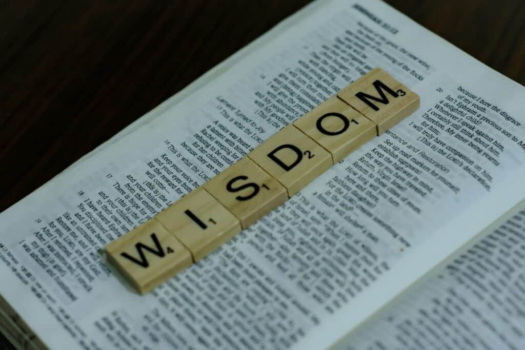 a scrabbled word spelling the word wisdom is down on top of a bible. Wealth and Wisdom