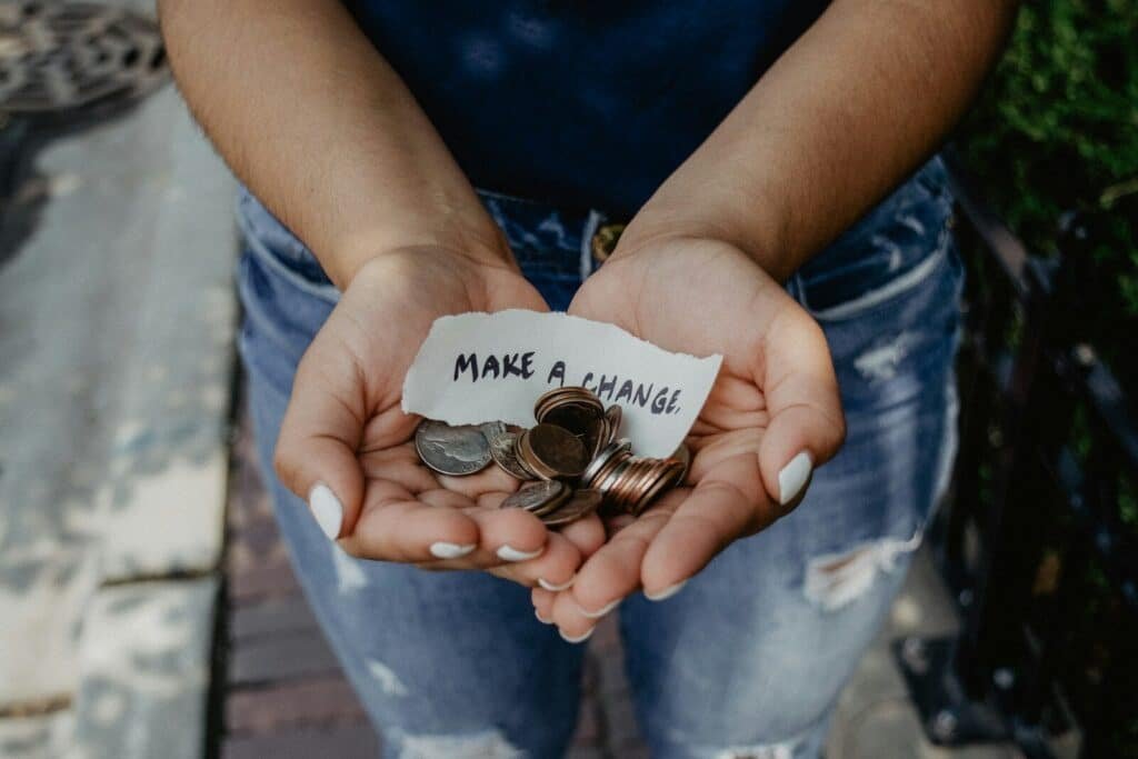 person showing both hands with make a change note and coins. Tithing best-kept secrets