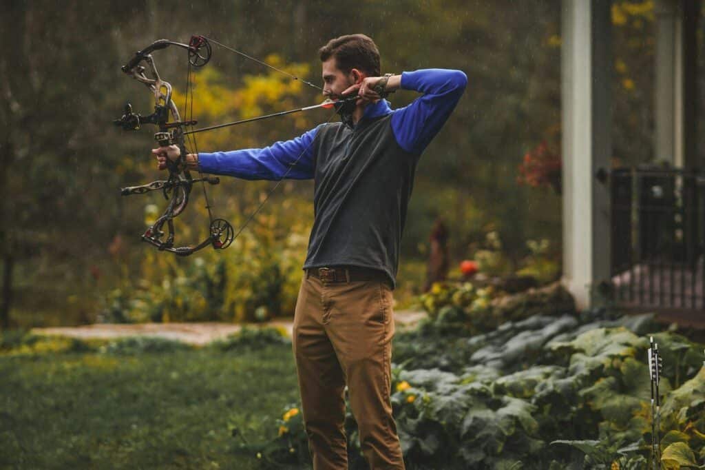 a man is holding a bow and aiming it. prayer to profit